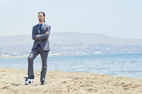 Бизнесмен с футболом на пляже — стоковое фото