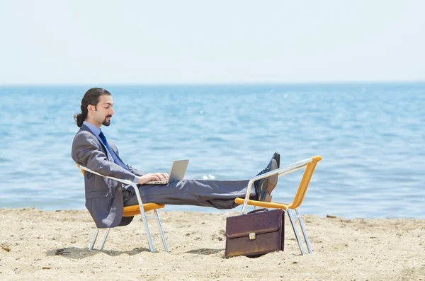 Young businessman lying on a deck chair with his laptop — Stock Photo ...