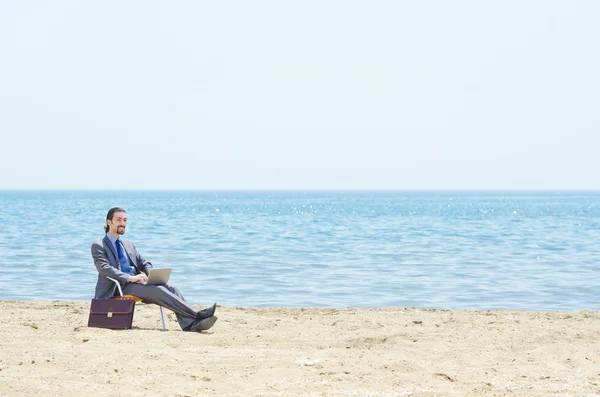 Бизнесмен, работающий над ноутбуком на берегу моря — стоковое фото