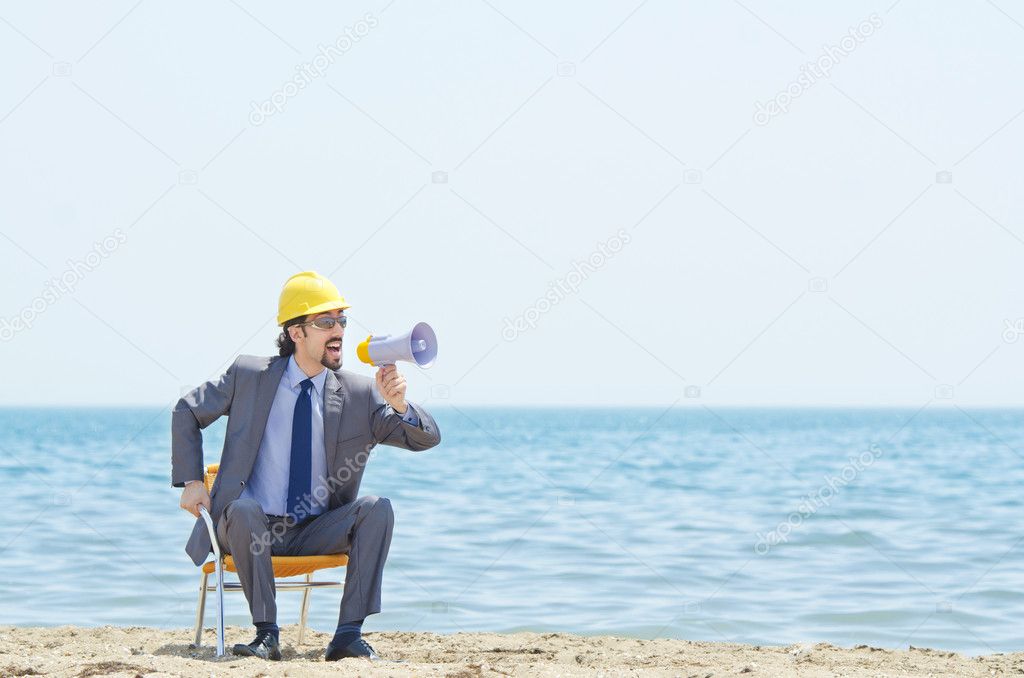 Man with hard hat and loudspeaker on beach