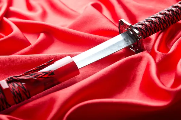 Japanskt svärd takana på röd satin bakgrund — Stockfoto