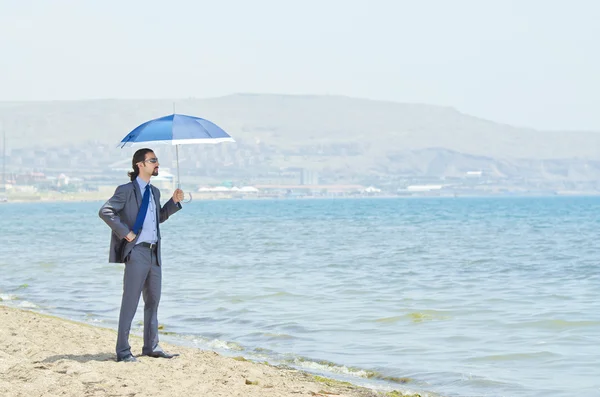 Uomo con ombrellone sulla spiaggia di mare — Foto Stock