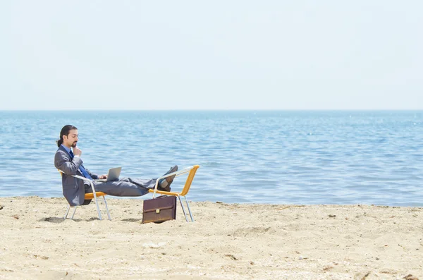 Uomo d'affari che lavora su laptop in riva al mare — Foto Stock