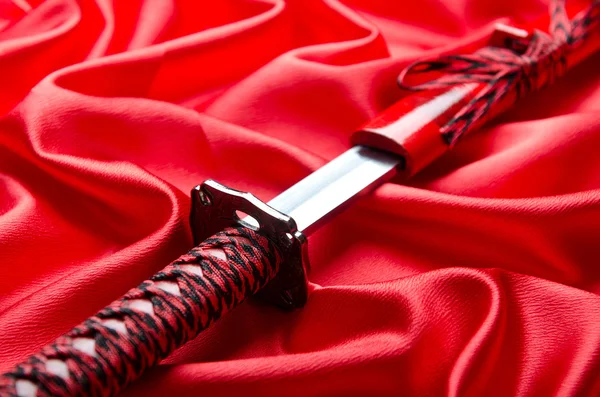 Japon kılıcı takana kırmızı saten zemin üzerine — Stok fotoğraf