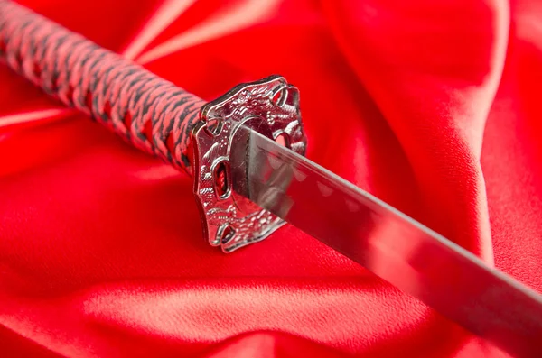 A japán kard takana piros szatén háttér — Stock Fotó