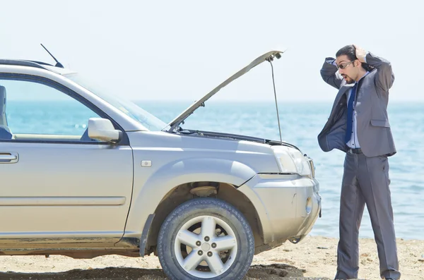 Человек с машиной на берегу моря — стоковое фото