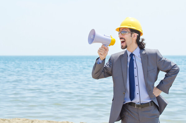 Man with hard hat and loudspeaker on beach