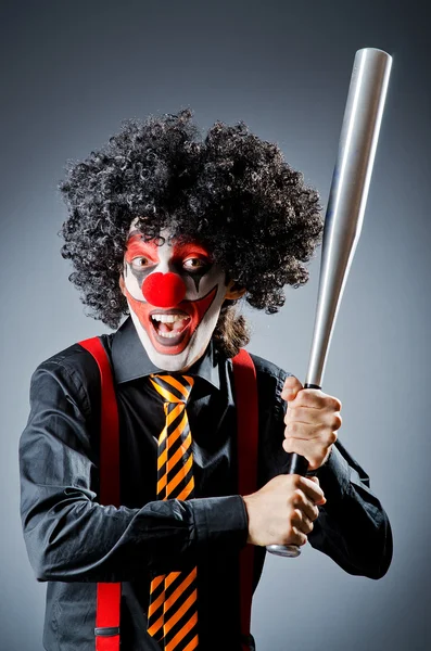 Funny clown with bat in studio — Stock Photo, Image