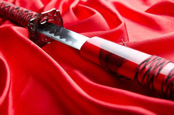 Japanskt svärd takana på röd satin bakgrund — Stockfoto
