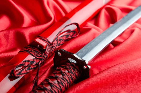 赤いサテンの背景に日本刀高菜 — ストック写真