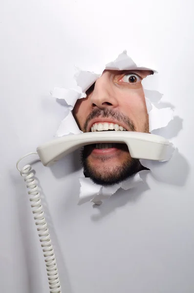 Man med telefon-mottagare genom hål papper — Stockfoto