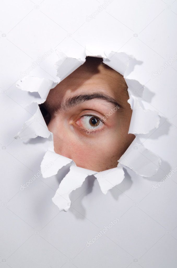 Male face through the hole in paper