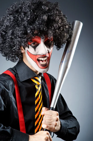 Funny clown with bat in studio — Stock Photo, Image