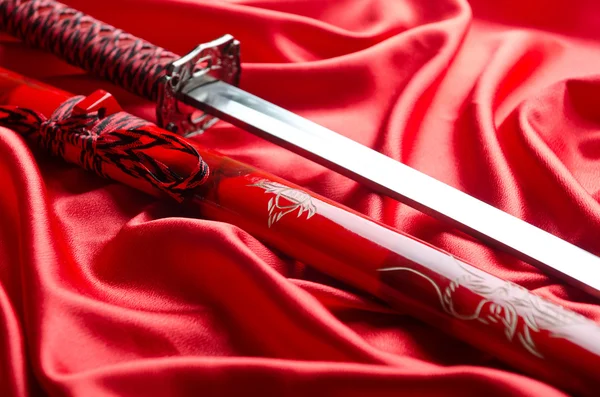 Japanese sword takana on red satin background — Stock Photo, Image