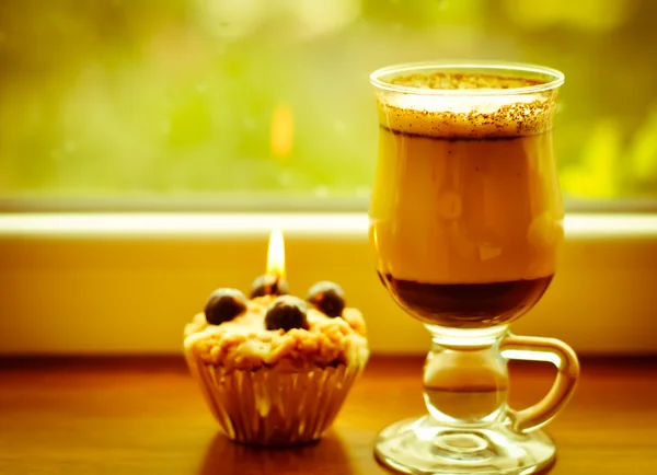 Kaffee Latte und eine brennende Kerze am verregneten Fenster — Stockfoto