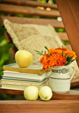 Books, fresh apples, and marigolds in a vase stock image clipart