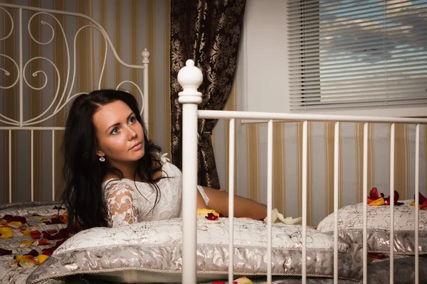 Atraktivní brunetka ležící na posteli — Stock fotografie