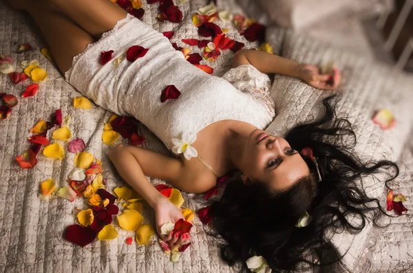 Seksuele brunette liggend op een bed — Stockfoto