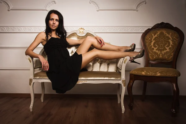 Atraktivní bruneta sedí na gauči — Stock fotografie