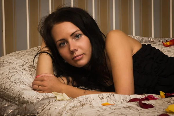 Attractive brunette lying on the bed — Stock Photo, Image