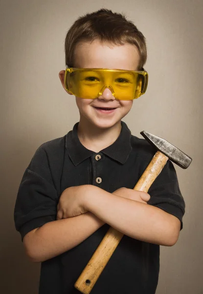 Menino de óculos com um martelo — Fotografia de Stock