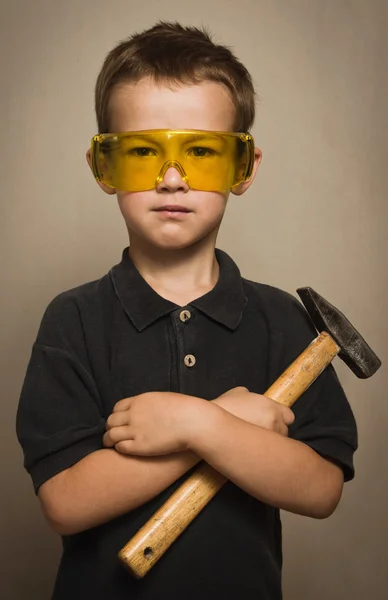 Menino de óculos com um martelo — Fotografia de Stock