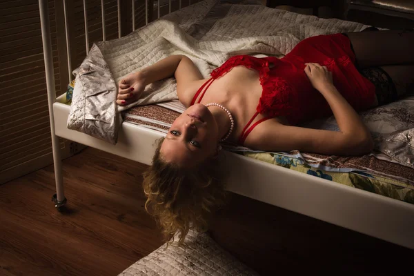 Sexual blonde in red lying on a bed — Stock Photo, Image