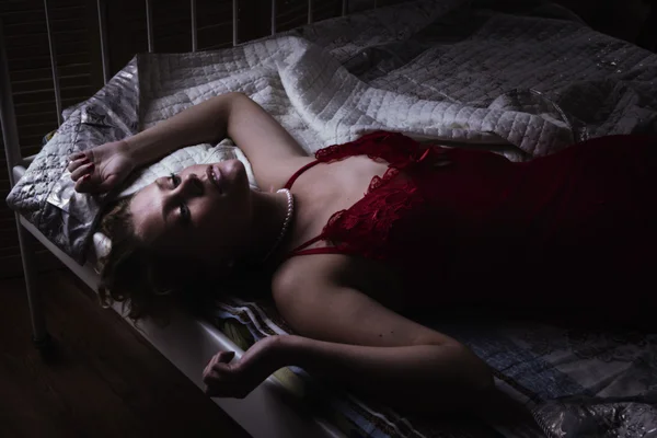 Blondine in Rot auf einem Bett liegend — Stockfoto