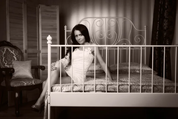 Morena atraente sentada na cama — Fotografia de Stock