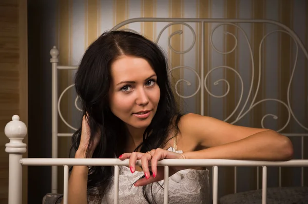 Attractive brunette sitting on the bed — Stock Photo, Image