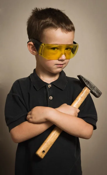Мальчик в очках с молотком — стоковое фото