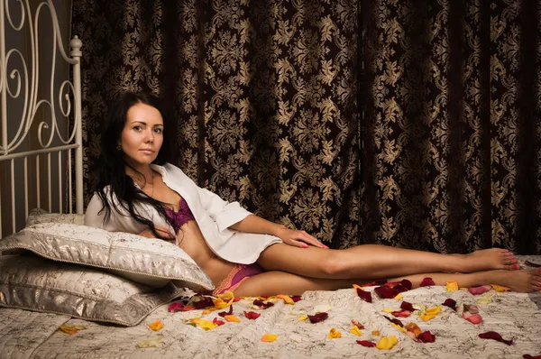 Atraktivní brunetka ležící na posteli — Stock fotografie