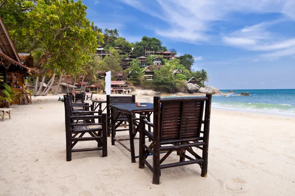 Cadeiras e mesa na praia de areia com céu azul — Fotografia de Stock