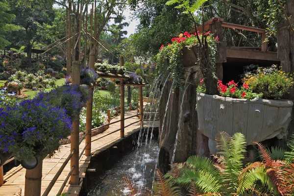 Bambuspfad zwischen Brunnen und Blumenbeeten — Stockfoto