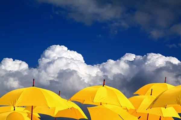 Yellow umbrellas on cloudy background — Stock Photo, Image