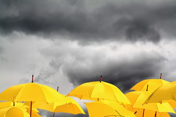 Yellow umbrellas on cloudy background — Stock Photo, Image