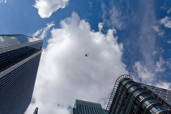 De hemel met vliegtuig omringd door wolkenkrabbers — Stockfoto