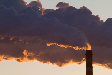 A steaming power plant pipe against sunset sky clipart