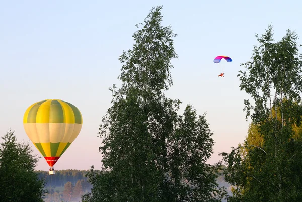 Air balloon and a paraglider above the forest — Stock Photo, Image