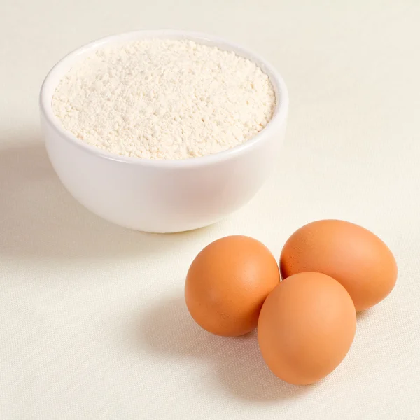 Œufs et farine de blé dans une assiette sur fond blanc — Photo