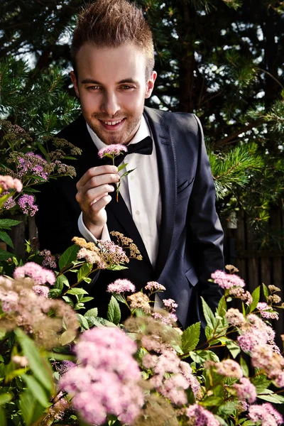 Portrait of young beautiful fashionable man against summer garden. — Stock Photo, Image