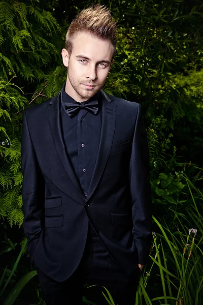 Retrato de jovem belo homem elegante contra jardim de verão . — Fotografia de Stock