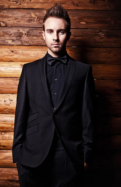 Portrait of young beautiful fashionable man against wooden wall. — Stock Photo, Image