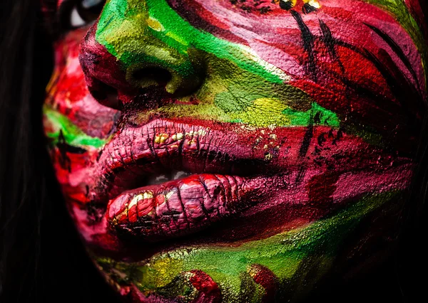 Nahaufnahme Porträt einer künstlerischen Frau, die mit roter und grüner Farbe gemalt wurde. Teil des Gesichtsfotos. — Stockfoto