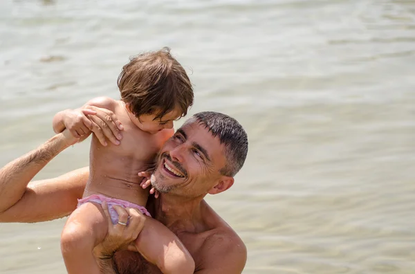 Far og datter afslappende og sjov på stranden, Italien - Stock-foto
