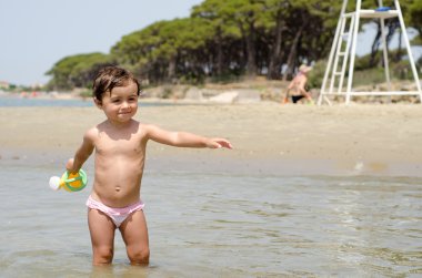 bir kova su ile kumsalda oynarken mutlu bebek