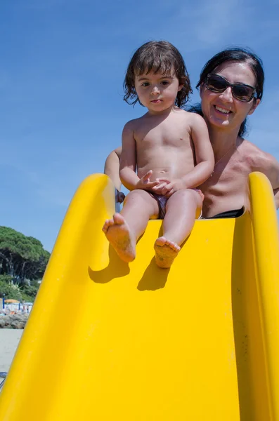 Joyeux bébé fille sur Slide aire de jeux avec sa mère — Photo