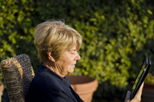 Пенсионерка отдыхает на свежем воздухе со своим планшетом — стоковое фото
