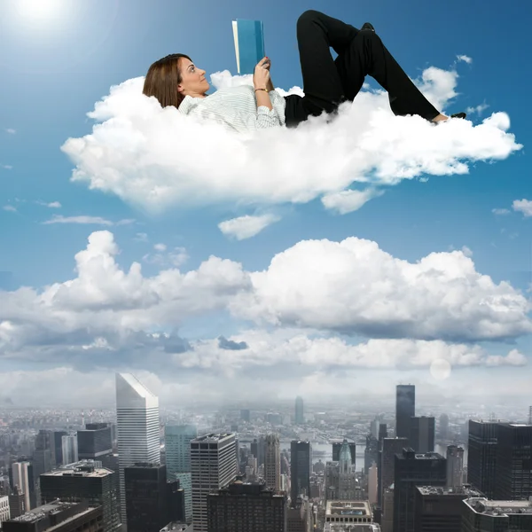 Businesswoman reading book on a cloud — Stock Photo, Image