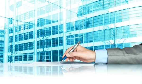 Businessman signing contract against modern offices — Stock Photo, Image